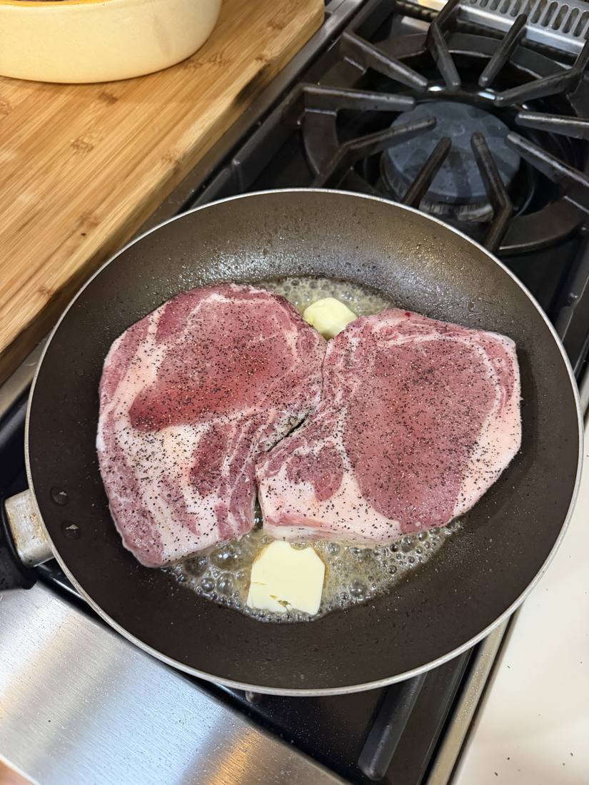 Thick-cut pork chops going into a hot pan